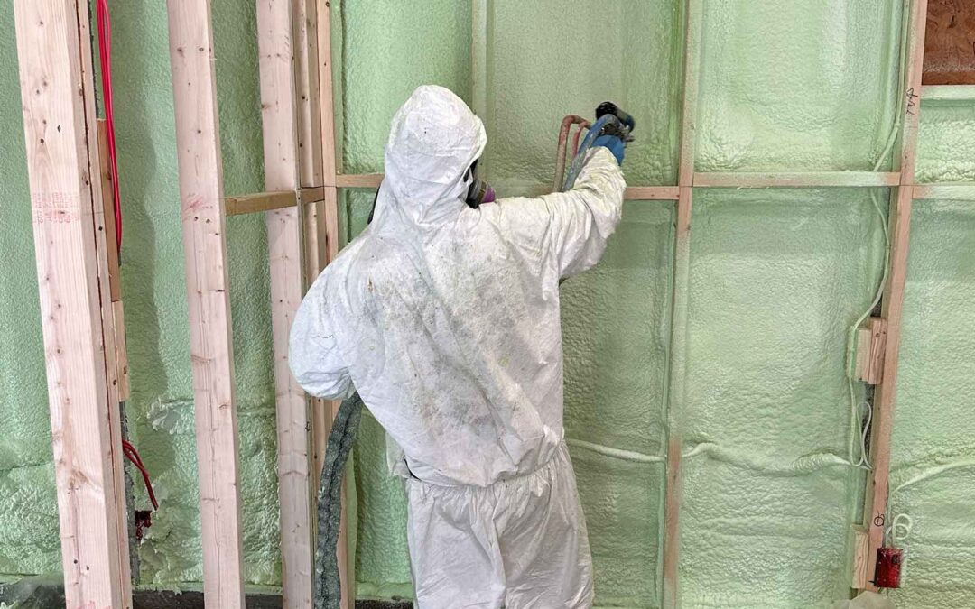 Team member of C&K Fibertech dressed in protective suit and installation spray foam insulation in wall.